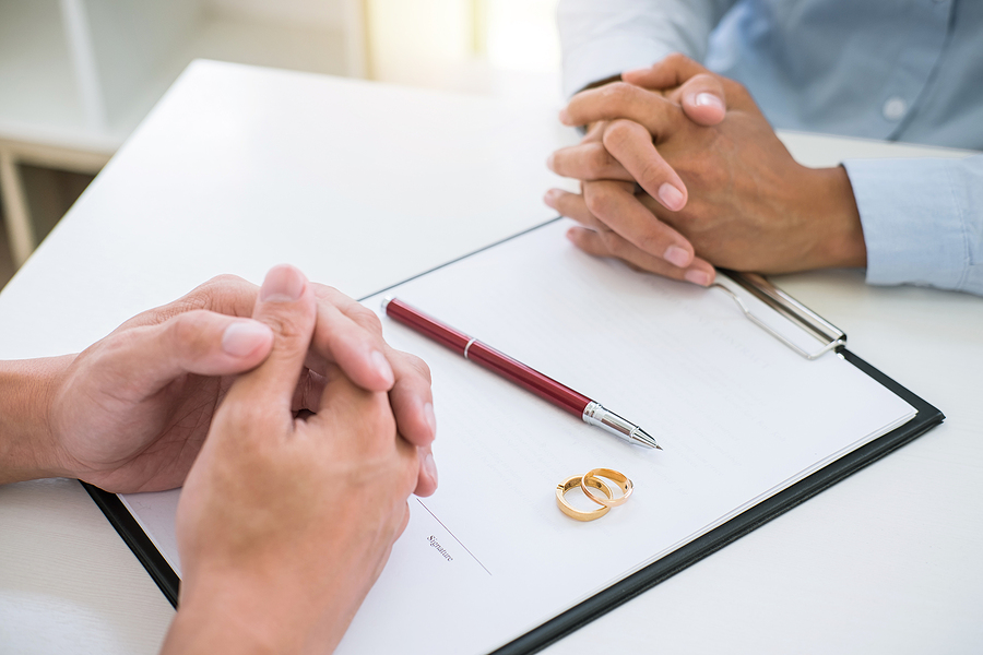 Husband and wife are reading divorce agreement and signing decree of divorce (dissolution or cancellation) of marriage filing divorce papers and two golden marry ring. Permanent Spousal Support